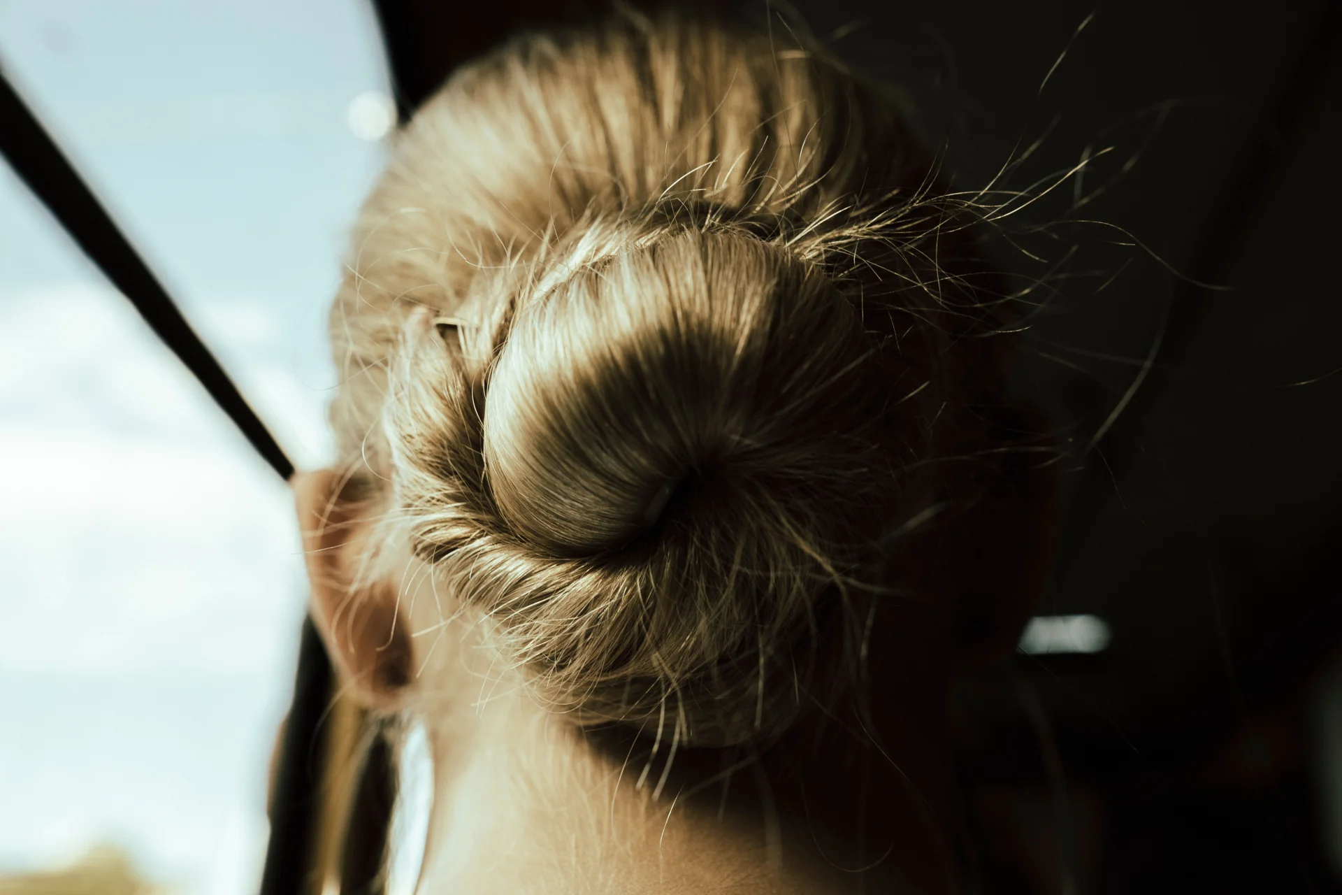 Zbliżenie na blond kok, oświetlony promieniami słońca, prezentujący elegancką fryzurę.